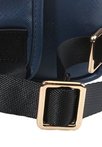 Materiale testurizzato di colore blu scuro con una forma strutturata, dotato di una cinghia nera e una fibbia rettangolare dorata per la chiusura.