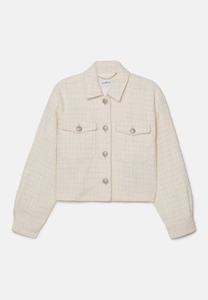 Veste courte crème en tissu texturé avec un motif en grille. Elle se caractérise par des boutons en argent, deux poches poitrine et un col classique.