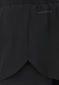 Mustat juoksushortsit, joissa on venyvä elastinen vyötärö, kerrostettu muotoilu ja hillitty logo. Sujuva pinta kevyestä kankaasta.