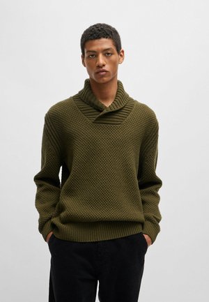 Suéter de punto en verde oliva oscuro con un patrón texturizado, amplio cuello doblado y corte relajado. Combina con pantalones de pana negros.