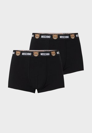 To sorte boxershorts med elastisk talje med Moschino tekst og bamseansigtsmønster på en lysegrå baggrund.