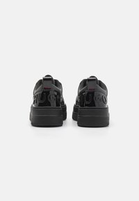 Schwarze Sneakers mit glattem, lackierten Finish, ausgestattet mit erhabenen Logodetails, gepolstertem Schaft und Gummisohle mit strukturiertem Grip.