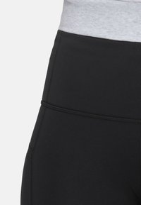 Black leggings with a gray elastic waistband, featuring flat seams and a smooth texture, designed for comfort and flexibility.