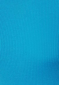 Gros plan sur un tissu tricoté côtelé bleu vif avec des lignes texturées verticales.