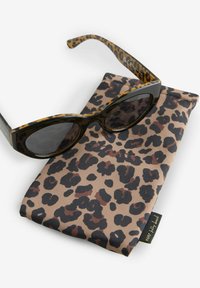 Zonnebril met luipaardpatroon, donkere lenzen en zwarte accenten op het montuur, rustend op een bijpassende case met luipaardprint van structuurstof.