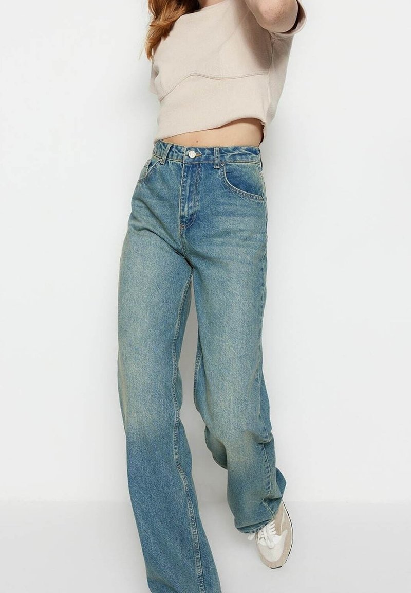 Jean en denim bleu clair à taille haute, présentant une coupe droite, un lavage délavé et un design classique à cinq poches.