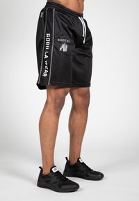 Zwarte sportshorts van een netstof materiaal; heeft een witte trekkoord, zijstrepen met "GORILLA WEAR" en een logo aan de voorkant.