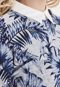 Grijze trui met een blauw palmbladpatroon en een witte kraag, gemaakt van een textuurstof met een relaxte pasvorm.