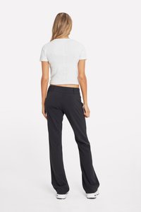 Fehér, rövid ujjú crop top kerek nyakrésszel; fekete, bő szabású nadrággal párosítva. Simaság, testhezálló szabás és letisztult vonalak jellemzik.