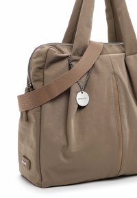 Beige weiche Stoffhandtasche mit doppelten Griffen, einem Schulterriemen, einer Reißverschlusstasche auf der Vorderseite und einem runden Metallanhänger mit der Gravur "SURIFREY".