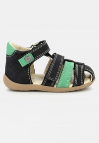 Chanclas negras y verdes con diseño abierto, que cuentan con correas ajustables, detalles de costura y una suela de goma marrón. Adecuadas para niños.