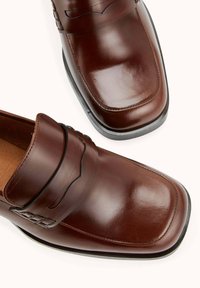 Mocassins en cuir marron avec un bout carré, texture lisse, accents cousus et semelle intérieure rembourrée. Semelle en caoutchouc noir pour une meilleure adhérence.