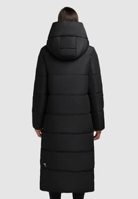 Geacă puffer neagră cu glugă, având o siluetă lungă, dreaptă și un design matlasat. Materialul are o textură netedă cu umplutură vizibilă.