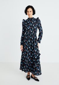 Vestido longo preto com mangas com volantes e cintura elástica, apresentando um padrão floral colorido com realces em azul, vermelho e branco.