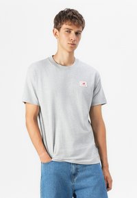 Grå kortermet T-skjorte med rund hals og en liten rød logoemblemet på venstre side. Laget av mykt stoff, har en avslappet passform.