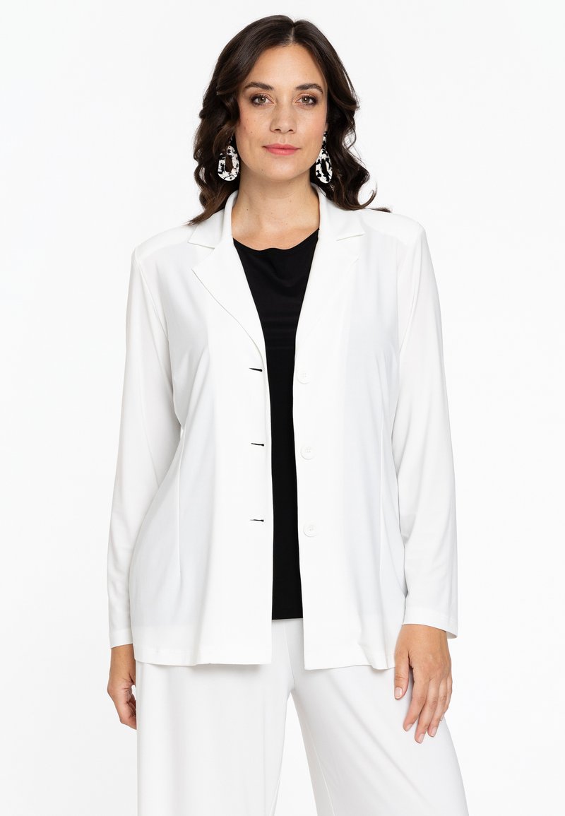 Witte blazer met lange mouwen en een gelapte kraag, voorzien van een sluiting met vijf knopen, gecombineerd met een zwarte top. De stof lijkt glad en heeft een relaxte pasvorm.