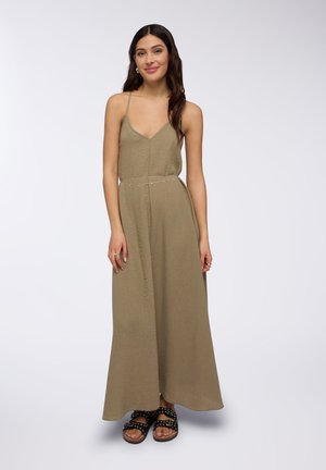 Abito maxi in verde oliva, tessuto texturizzato, con scollo a V e spalline sottili. Dettaglio in catena argentata in vita. Sandali neri con borchie.