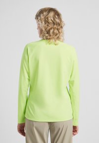 Maglietta a maniche lunghe in tessuto leggero di un luminoso verde neon, con scollatura rotonda e maniche raglan, caratterizzata da una texture liscia.