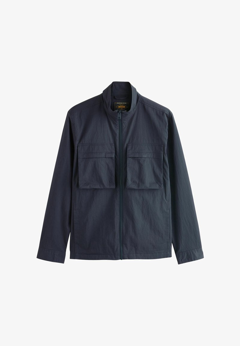 Giacca leggera di un blu scuro con zip frontale e due grandi tasche sul petto con patta, mostrata su uno sfondo bianco.