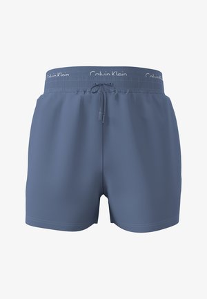 Bañadores cortos azules para hombre con cintura elástica, cordón y marca visible de Calvin Klein en la cintura interior.