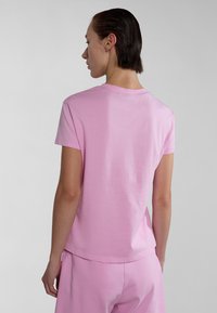 Camiseta de algodón rosa con mangas cortas, cuello redondo y corte relajado. Detalle de costura mínima, combinada con pantalones a juego.