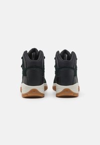 Hoge sneakers met zwart gestructureerd stof, gewatteerde kraag en contrasterende gumrubberen buitenzool. Subtiele ontwerpelementen aan de zijkanten.