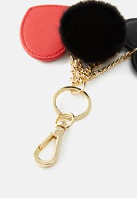 Keychain accessory with red and black faux leather, a black fur pom-pom, gold hardware, chain link, and lobster clasp for attachment.