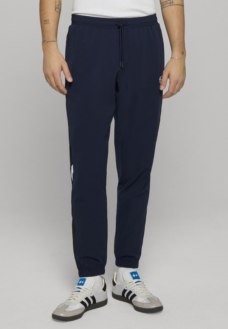 Donkerblauwe, lichtgewicht sportbroek met een elastische tailleband en trekkoord, voorzien van zwarte strepen aan de zijkant en een logo op het linker bovenbeen.