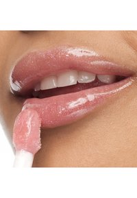 Błyszczący różowy błyszczyk do ust nałożony aplikatorem w kształcie stópki jelenia, podkreślający gładką, lekko połyskującą teksturę pełnych ust na tle ciepłej karnacji.