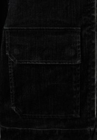 Černá džínová bunda s předním zipovým zapínáním, jednou náprsní kapsou s klopou a kontrastním šitím. Hladká textura po celé ploše.