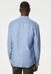 Camicia azzurra chiara a maniche lunghe, realizzata in lino texturizzato, con un yoke posteriore e polsini con bottone, e orlo curvo.