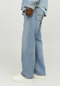 Lichtblauwe, wijde denim jeans met een rafelige zoom en achterzakken. Gecombineerd met witte sneakers, wat een casual stijl laat zien.