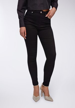 Czarne skinny jeans o gładkiej fakturze, wysoki stan i minimalistyczny design. W połączeniu z błyszczącymi, szpiczastymi szpilkami.