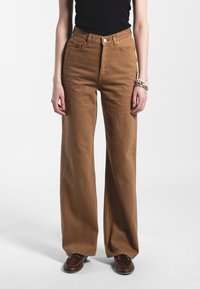 Jeans larghi a vita alta marroni con tasche frontali e posteriori, realizzati in robusto denim di cotone, dotati di chiusura con bottone e passanti per cintura.