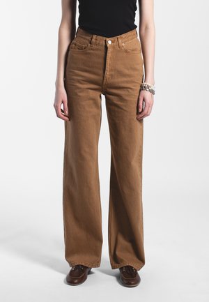 Vaqueros de tiro alto y pierna ancha en color marrón, con bolsillos delanteros y traseros, confeccionados en resistente denim de algodón, y que cuentan con cierre de botón y pasadores para cinturón.