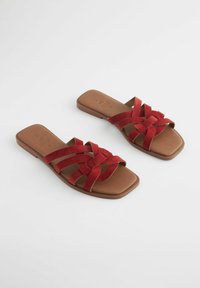 Røde ruskinds slide-sandaler med et krydset stropdesign, der har en firkantet tå og en brun gummisål. Glat tekstur og minimal udsmykning.