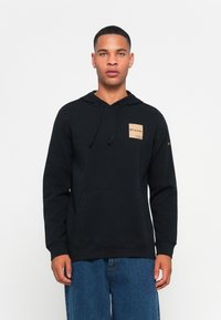 Felpa con cappuccio nera realizzata in misto cotone, con tasca frontale e un piccolo logo beige sul lato sinistro del petto. Vestibilità rilassata.