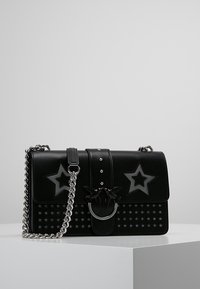 Borsa a tracolla in pelle nera con motivi a stella, tracolla in catena argento e un accentuato anello unico. Presenta una finitura liscia e borchie decorative.