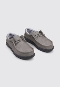 Grijze schoenen met een glad leren bovenwerk en een zwarte rubberen zool. Voorzien van een gestructureerde grijze voering en eenvoudige vetersluiting.