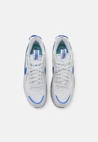 Vita sneakers med blå detaljer, strukturerad tyg, rund tå och stoppad innersula. Har snörning och varumärke på tungan och innersulan.