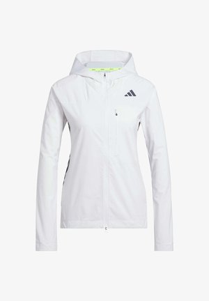 Biała kurtka zapinana na zamek z kapturem, wykonana z lekkiego materiału. Posiada czarne akcenty oraz kieszeń na piersi. Zawiera otwory wentylacyjne na rękawach.