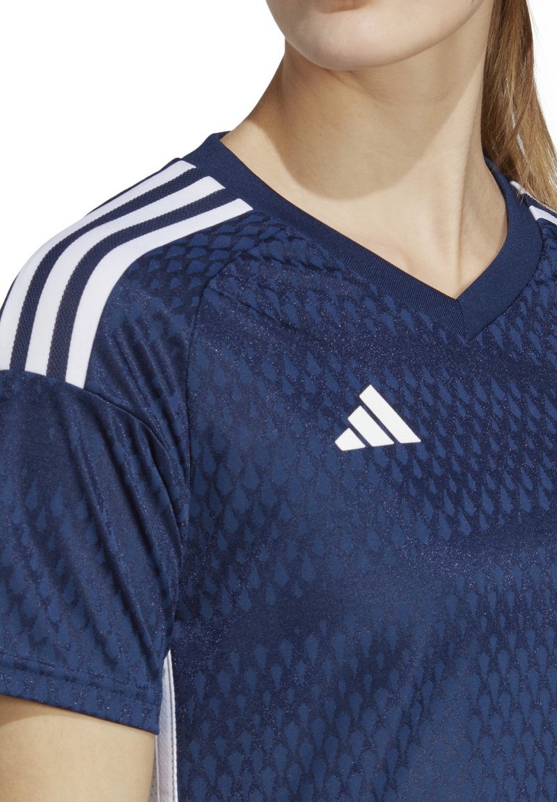 Maglietta atletica blu navy con un design texture, con strisce bianche sulle spalle e logo Adidas sul petto.