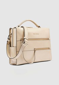 Beige leren handtas met een gestructureerd ontwerp, voorzien van meerdere ritsvakken, een afneembare schouderriem en accenten in goudkleurig metaal.