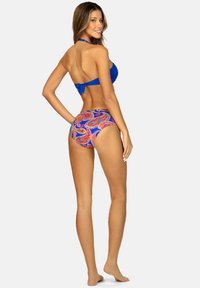 Niebieski biustonosz bikini z wiązaniem na szyi i detalem w postaci kokardy, w połączeniu z majtkami z wysokim stanem w kolorowy wzór paisley na niebieskim tle.