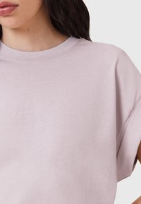 T-shirt di cotone rosa chiaro con scollatura tonda, maniche corte e tessuto morbido, caratterizzato da una vestibilità rilassata e dettagli di cucitura minimali.
