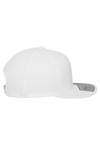 Fehér snapback sapka lapos karimával, hatpaneles kialakítással, kis felső gombbal és szellőző lyukakkal. Szürke belső címke található rajta.