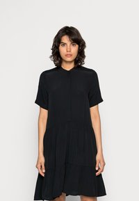 Vestido preto feito de tecido leve, apresentando um decote alto, mangas curtas e um design em camadas com uma silhueta fluida.