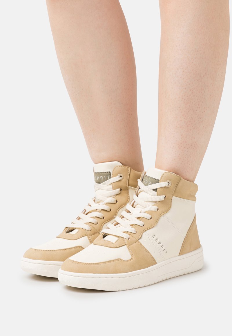Beige und cremefarbene High-Top-Sneaker aus verschiedenen Materialien, mit strukturierter Oberfläche, Schnürung vorne und Logoakzent auf der Zunge. Flache Gummisohle.