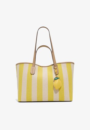 Sac cabas à rayures verticales jaunes et beiges avec des anses en cuir marron clair et un porte-clés en forme de citron accroché à une anse.
