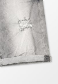 Shorts de mezclilla gris con un corte deshilachado en la rodilla, dobladillo doblado y textura suave. Presenta costuras sutiles y un aspecto desgastado.